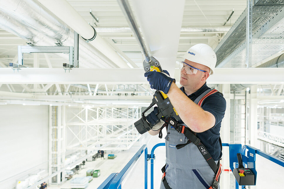 Leadec-Mitarbeiter bei der Installation der Medienversorgung an der Decke einer Fabrik.