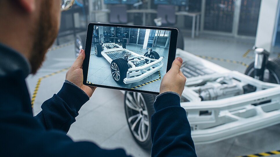 Jemand schaut über ein Tablet die Plattform eines Elektroautos an.