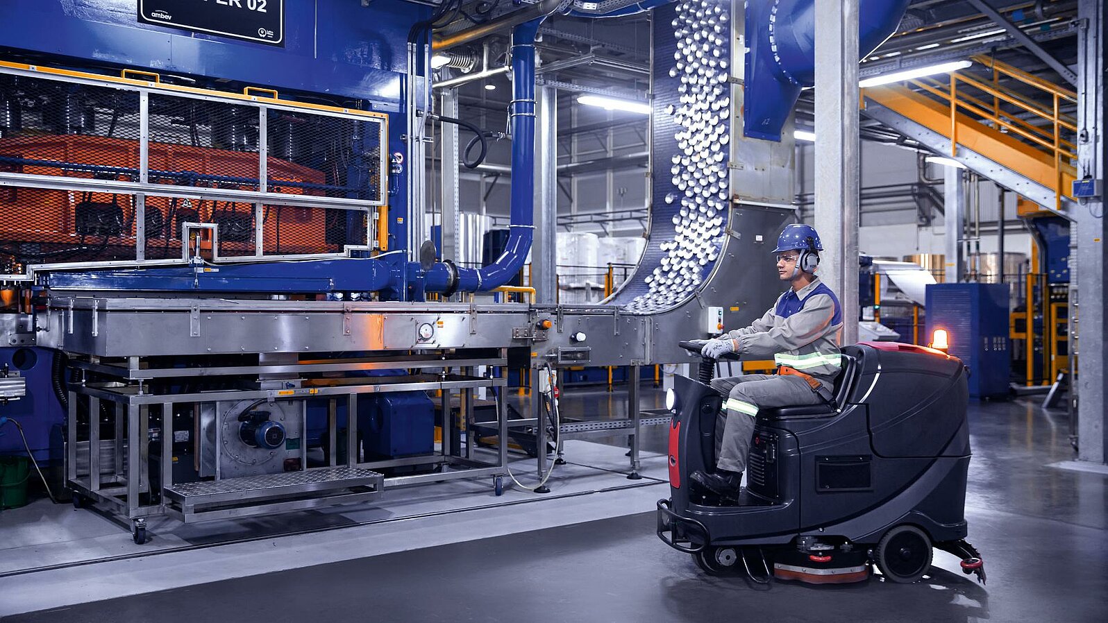 Ein Leadec-Mitarbeiter fährt eine Reinigungsmaschine durch den Produktionsbereich einer Lebensmittel- und Getränkefabrik.