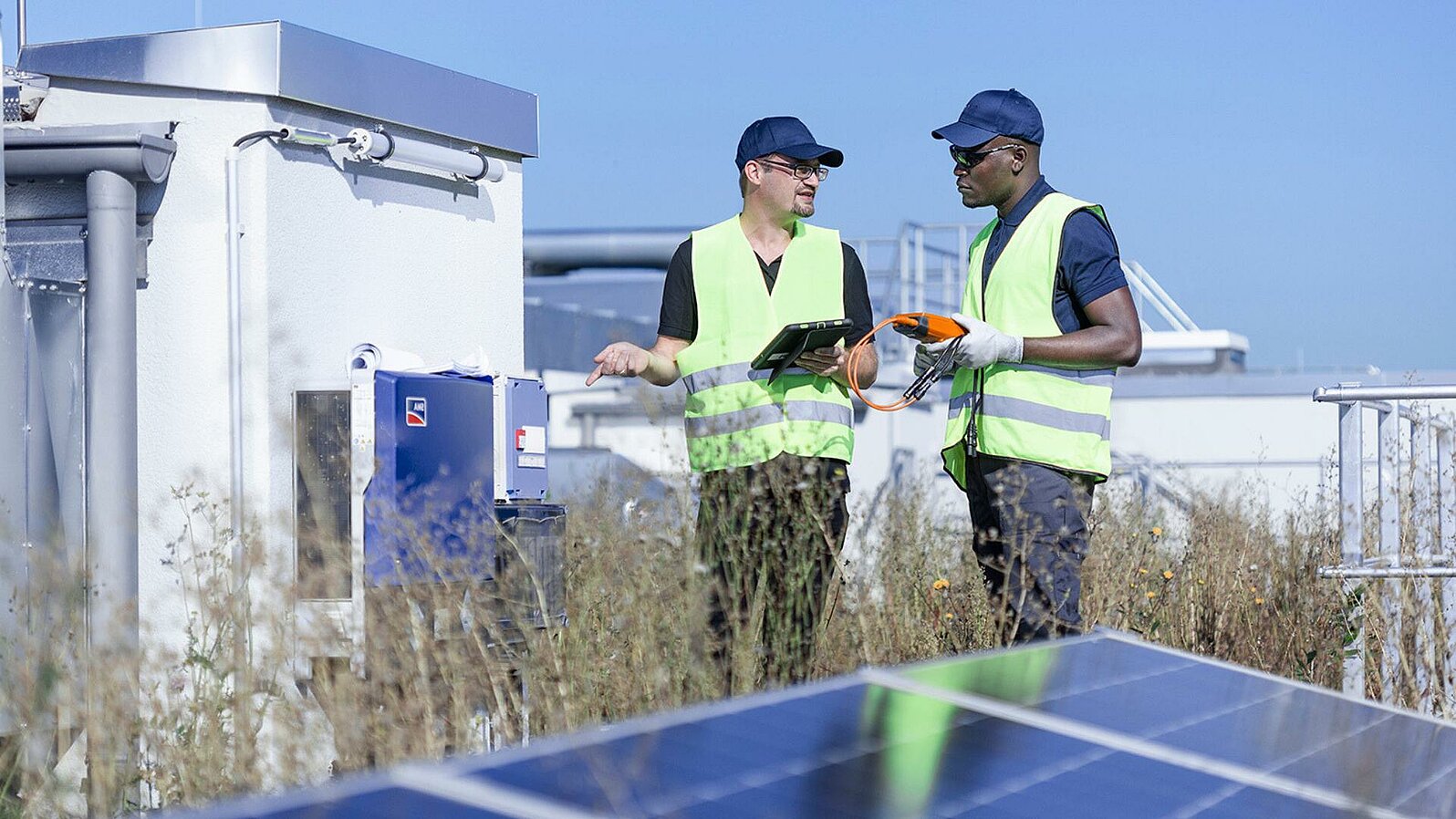 Zwei Leadec-Mitarbeiter auf einem Fabrikdach mit Photovoltaik-Modulen.