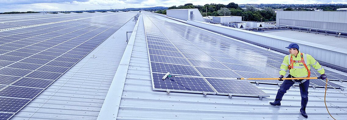 A Leadec employee cleaning the photovoltaic system on a factory roof.