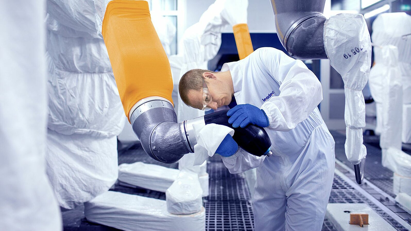 Leadec-Mitarbeiter reinigt Roboter in einer Lackieranlage.