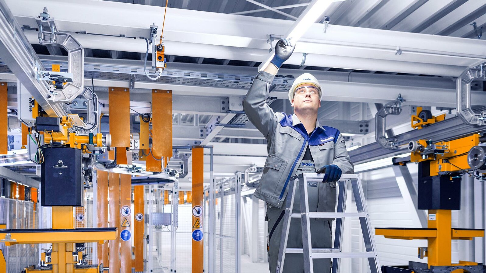 Person auf einer Leiter bei der Installation von LED-Beleuchtung.