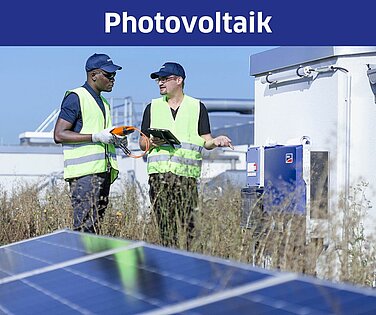 Zwei Männer auf einem Dach stehen an einer Photovoltaikanlage.