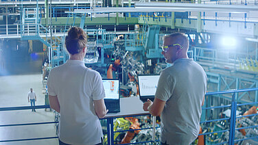 Two people with a laptop in a factory.
