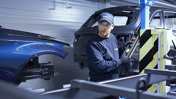 A Leadec employee troubleshooting the conveyor system in an automotive factory.
