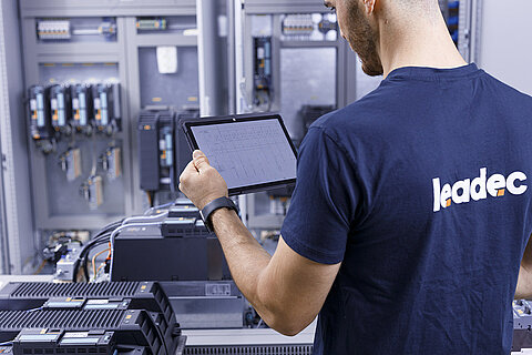 Leadec-Mitarbeiter mit einem Tablet bei der Überprüfung eines Schaltschranks.