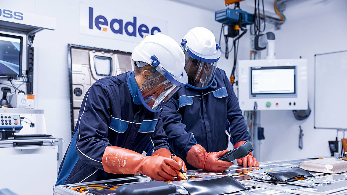 Two Leadec employees in protective clothing repairing a defective battery.