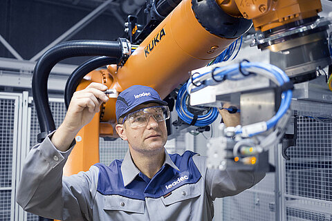 Ein Leadec-Mitarbeiter bei der Wartung eines Roboters in der Produktion.
