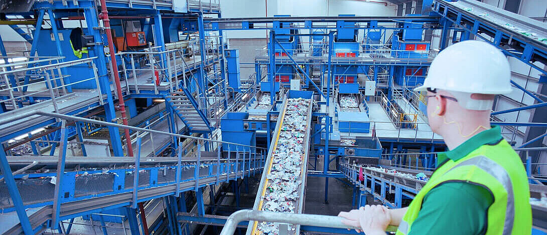 Employee with helmet standing in a waste sorting factory.