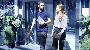 [Translate to Deutsch (DE):] Two Leadec employees coming out of the elevator at the Leadec office in Stuttgart.