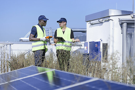 Zwei Leadec-Mitarbeiter auf einem Fabrikdach mit Photovoltaik-Modulen.