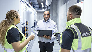 Das Leadec-Team im Gespräch in einem Fabrikkorridor.