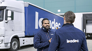 Zwei Leadec-Mitarbeiter unterhalten sich vor einem Lastwagen.