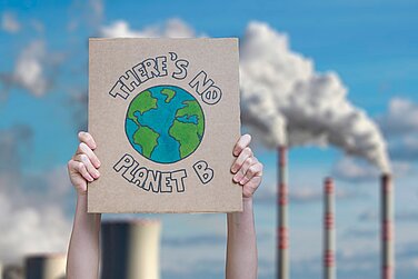 Zwei Hände halten ein Schild hoch mit der Aufschrift "There is no planet B"