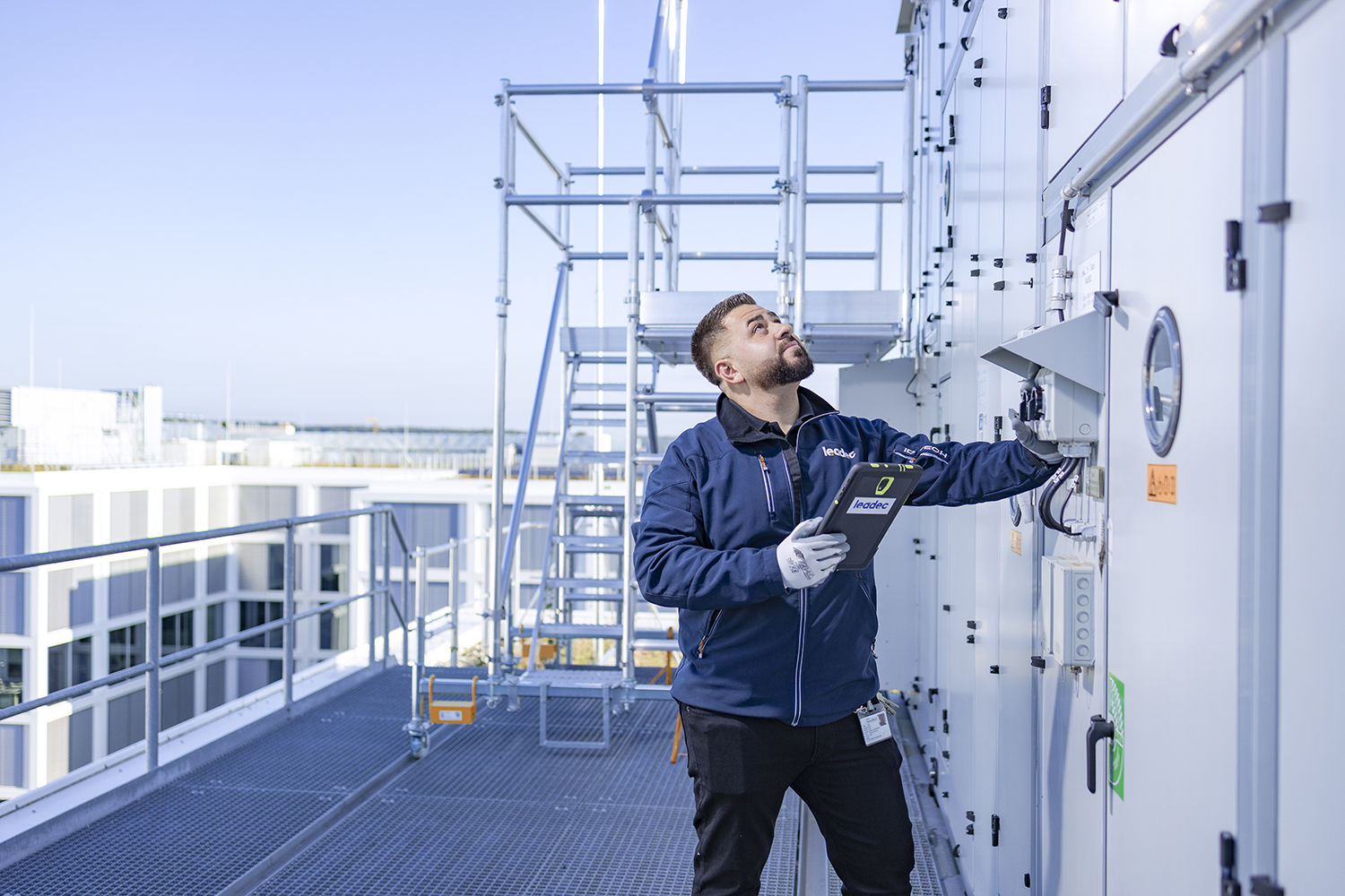 Leadec-Mitarbeiter auf einem Fabrikdach prüft die Außeninstallation der Lüftungsanlage.