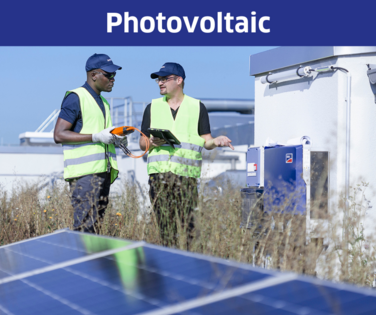 Two men on a roof standing by a photovoltaic system. 